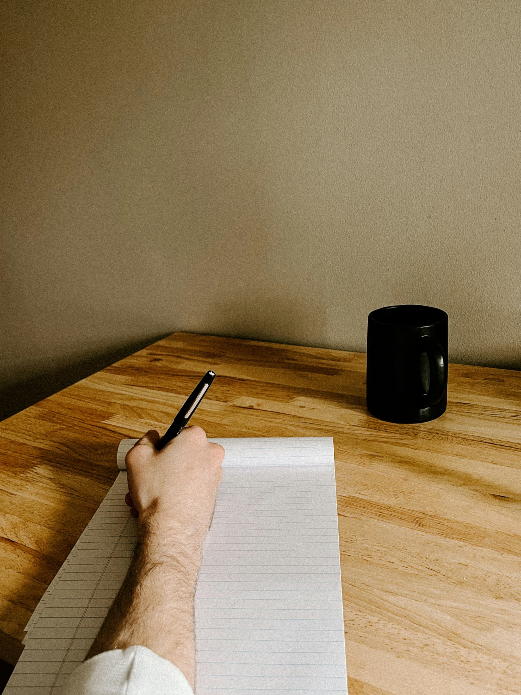 Twee mensen aan tafel, een van hen schrijft aantekeningen op papier